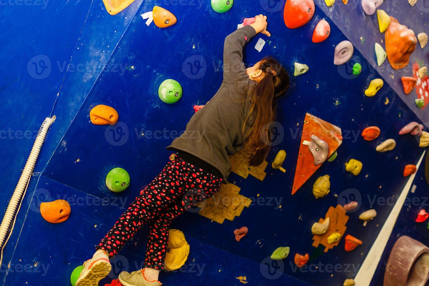 Little girl ascending in outdoor rock climbing gym photo