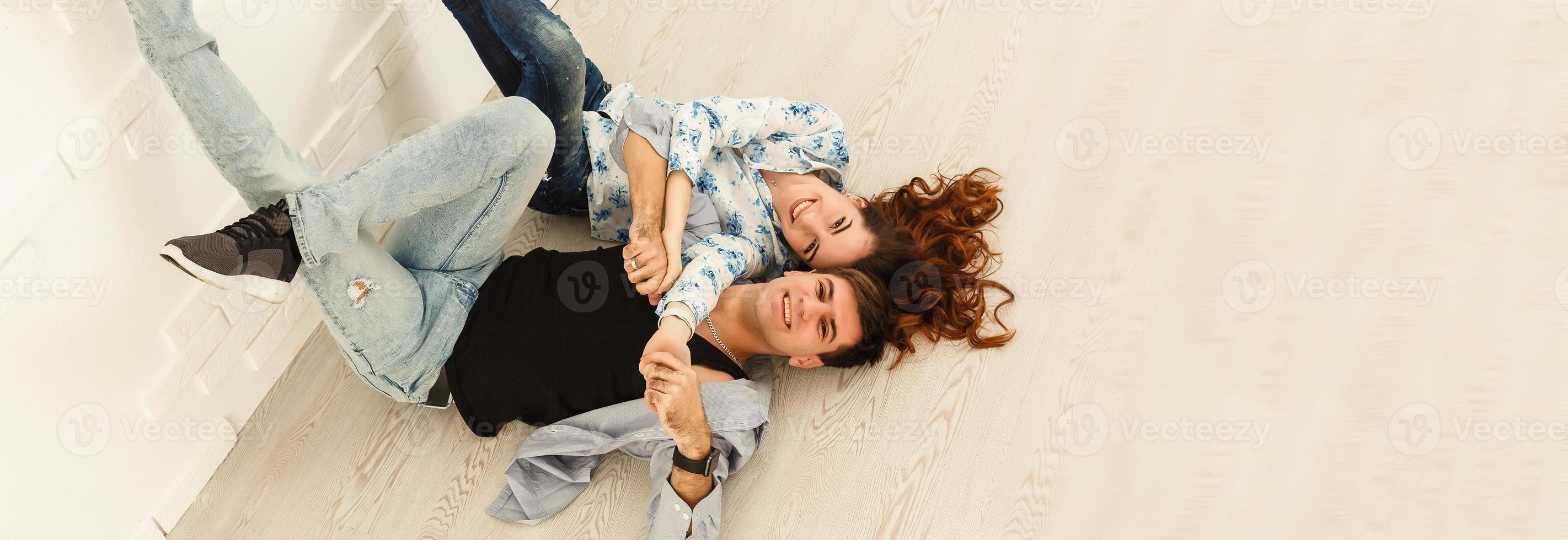 Happy young couple lying on the floor of new house and choosing color from palette photo