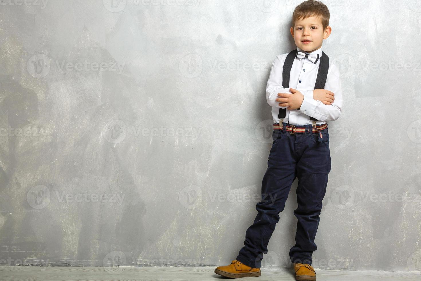 Elementary school student carrying notebooks over a gray background photo