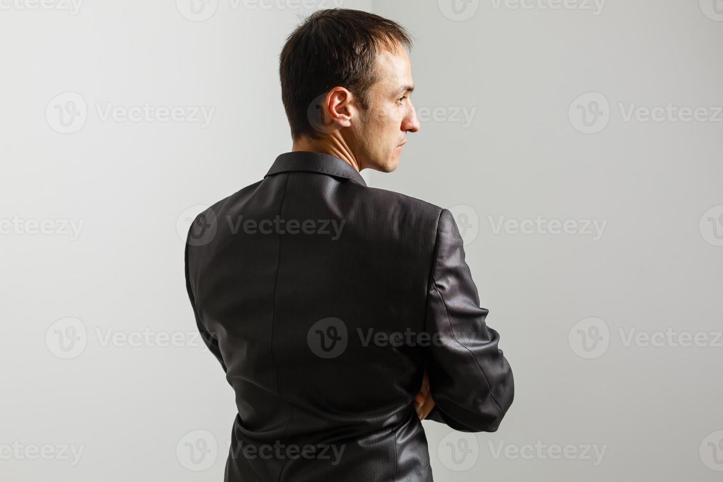 Cool businessman standing on grey background. photo