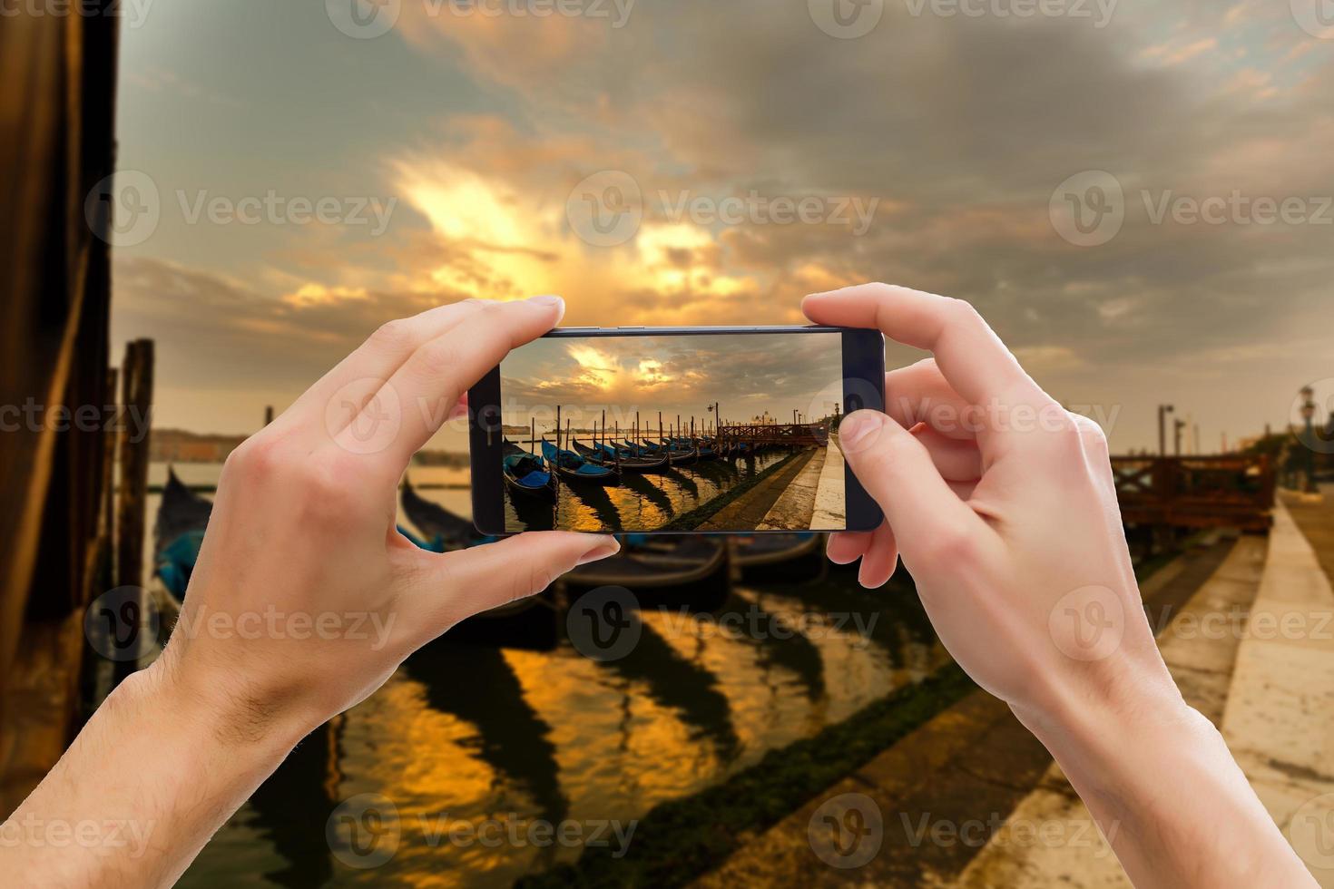 tomando fotografías en un teléfono inteligente móvil en góndola en el canal grande con una casa antigua clásica en el fondo, venecia, italia foto