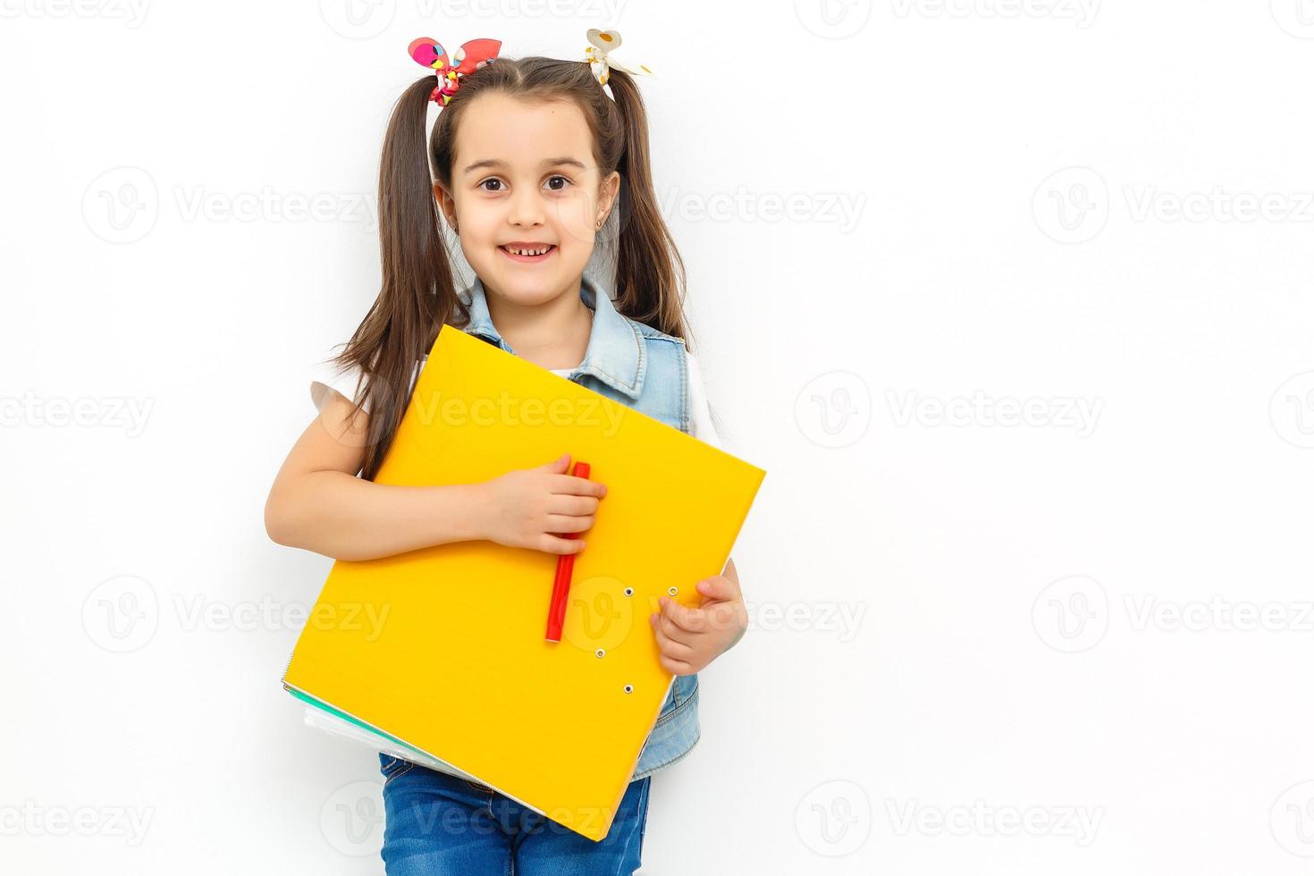 happy sweet little school girl carrying schoolbag backpack and books smiling in education and back to school concept isolated on white background photo