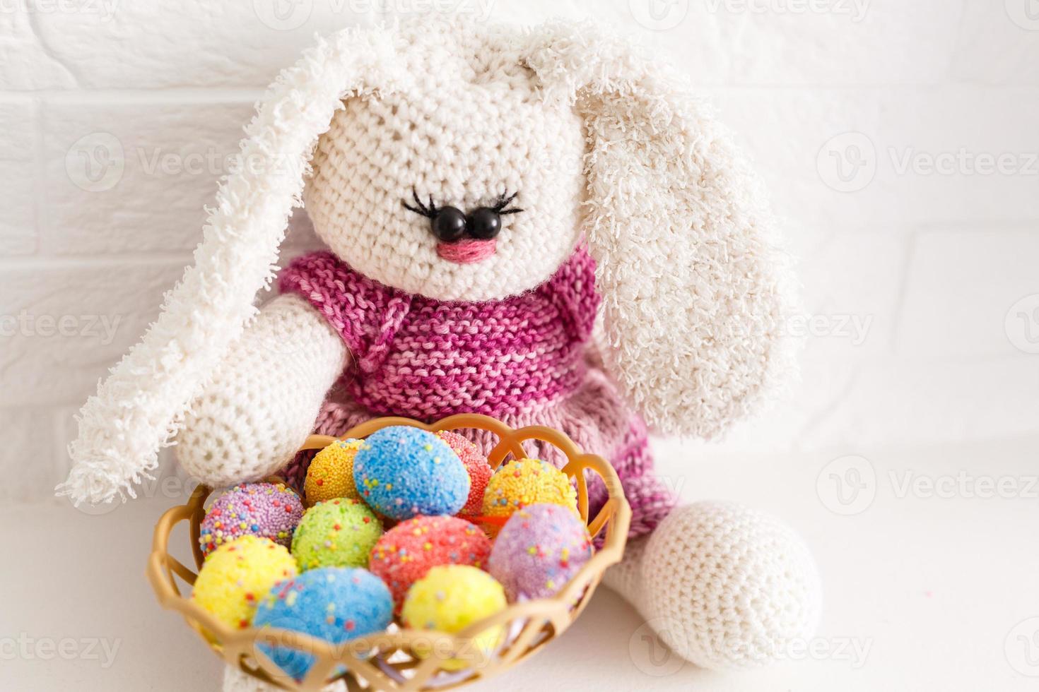 Funny little rabbit among Easter eggs in velour grass isolated on white photo