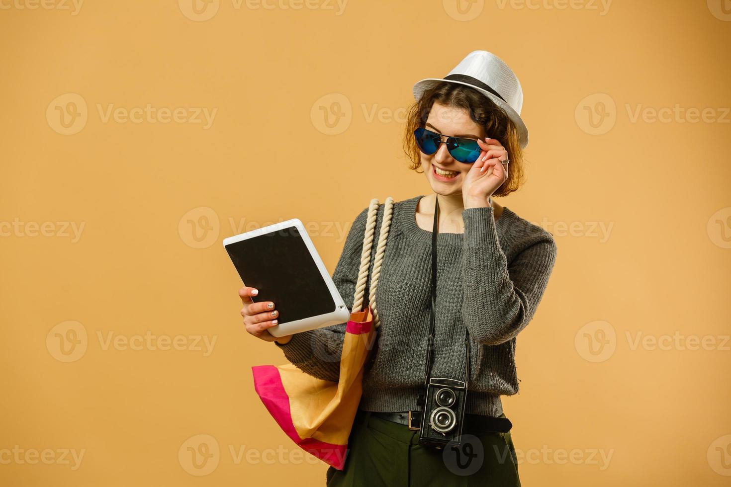Excited woman with tablet pc. Happy girl in white shirt using tablet, isolated on orange background photo