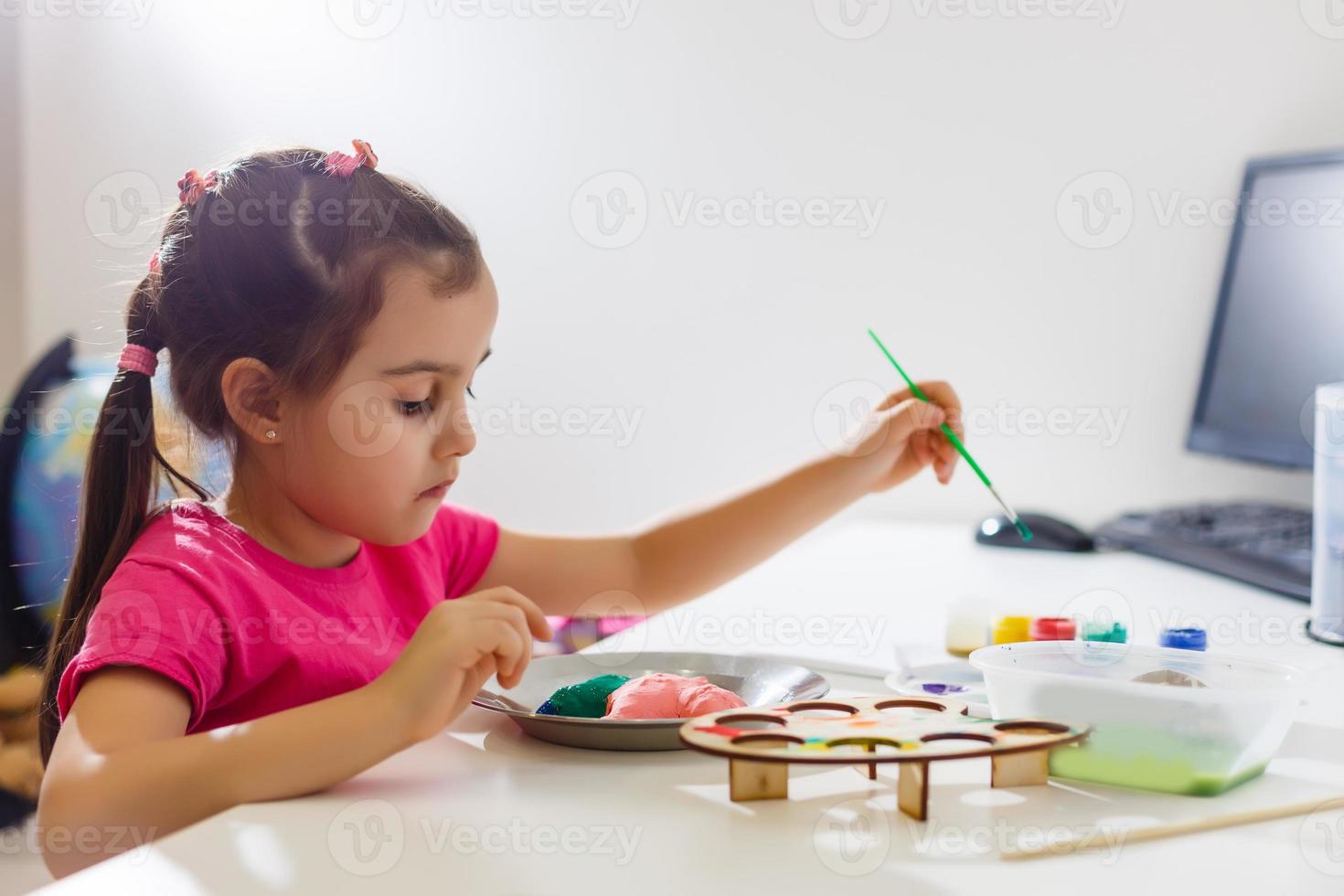 Little girl painting in her nursery at home photo