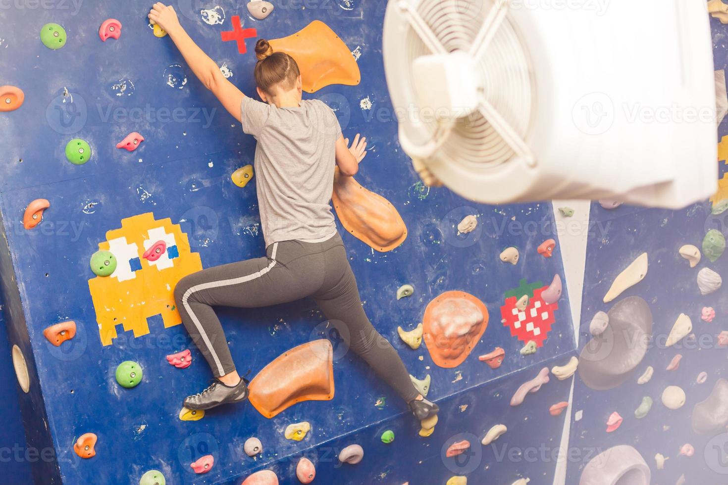 Young woman practicing rock-climbing on a rock wall indoors photo