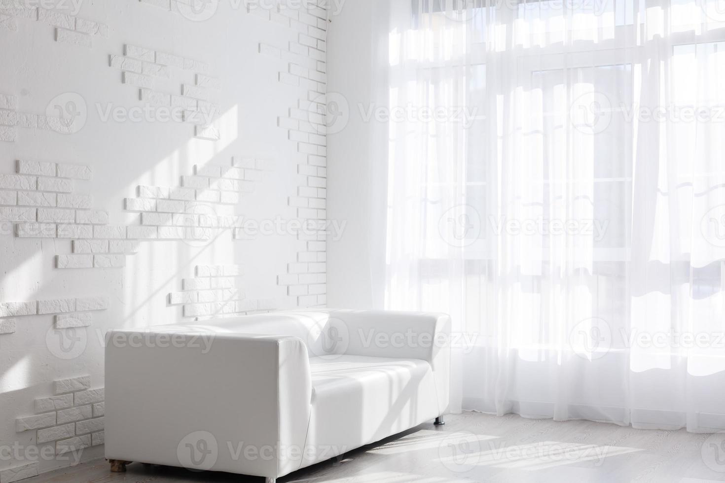 Bright, minimalist living room interior with white sofa standing near the window and black stool photo