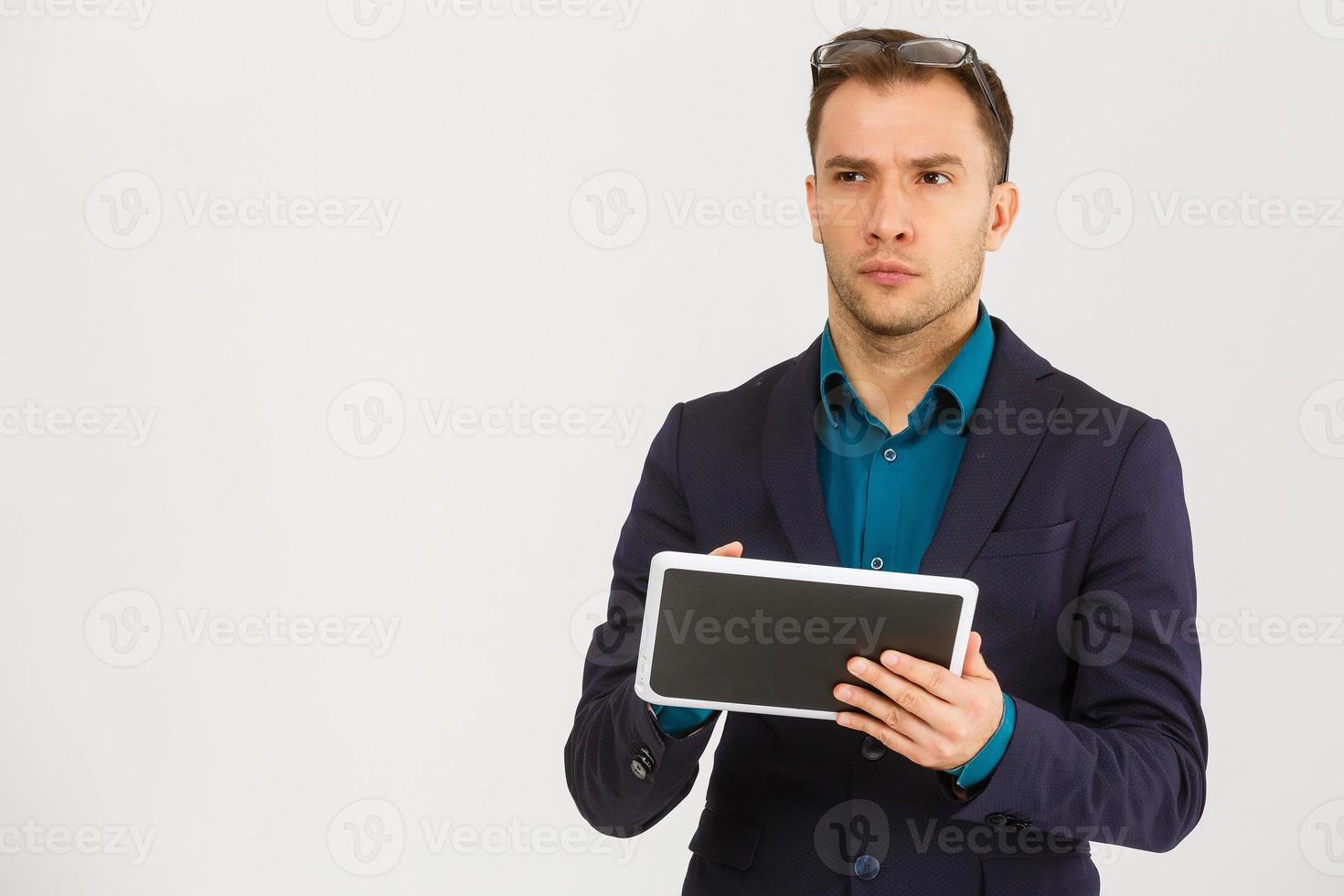 Using modern technologies. Handsome young man in shirt looking at his digital tablet and smiling while standing against  background photo