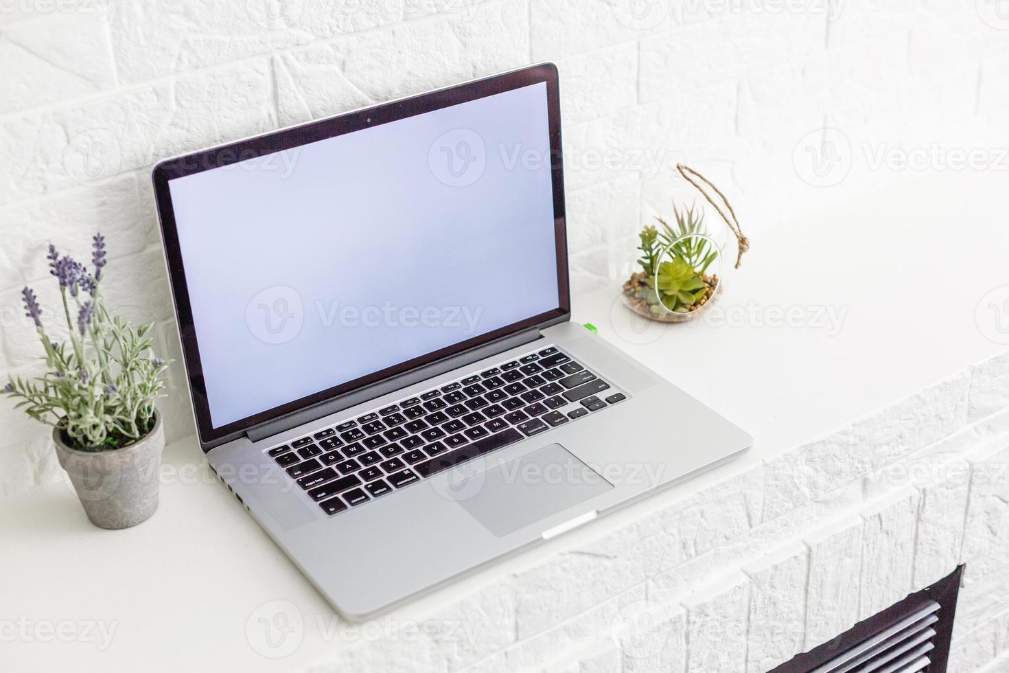 Laptop with blank screen on white table with mouse and smartphone. Home interior or office background photo
