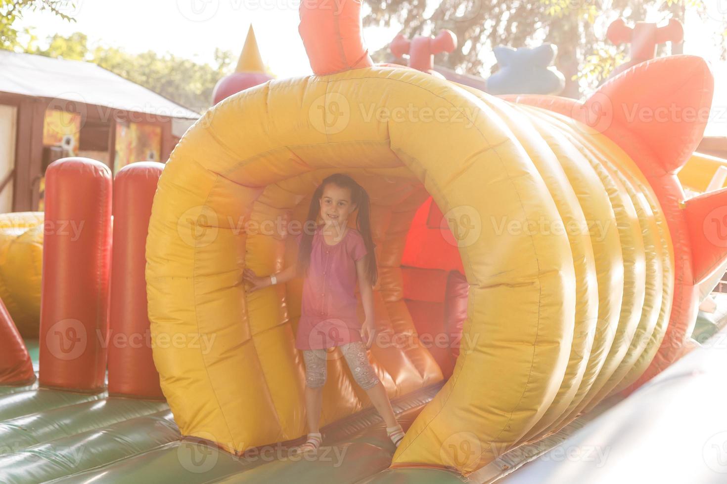 niña feliz divirtiéndose mucho en un castillo de salto durante el deslizamiento foto