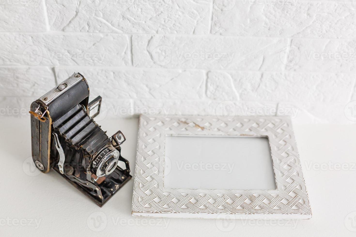 jarrones decorativos con flores y cámara antigua en un estante blanco sobre fondo de papel tapiz azul foto