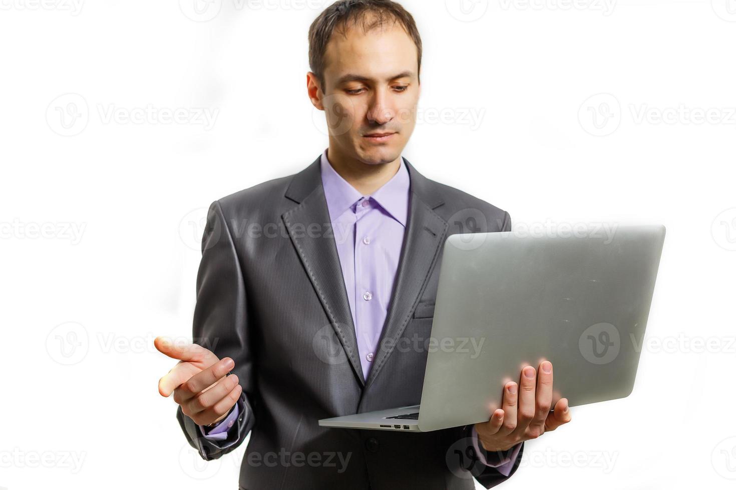 Working with joy. Handsome young man using his laptop and looking at camera with smile while standing against white background photo