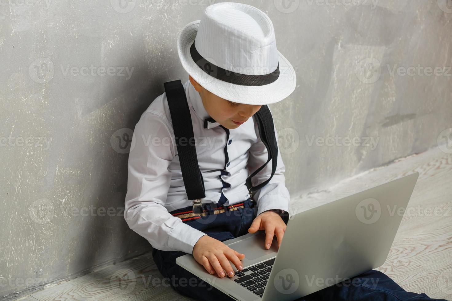 Young man sits on the laminate floor with black laptop. Top view photo