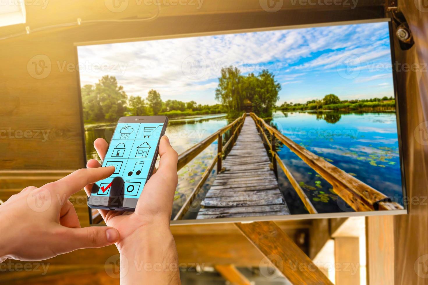 Happy attractive young man watching tv and using remote control at home photo