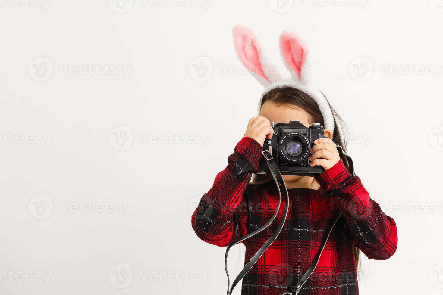 Surprised little girl wearing bunny ears, lying on light wooden floor on Easter Holiday. photo