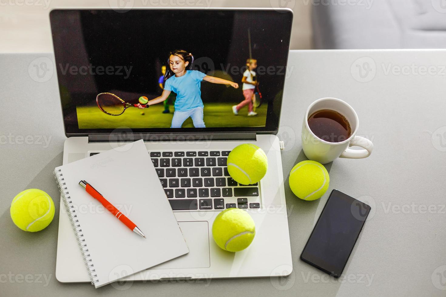 Sports tennis player with racket in blue costume. Woman atlete. Laptop on the table with design for bookmaker advertising photo