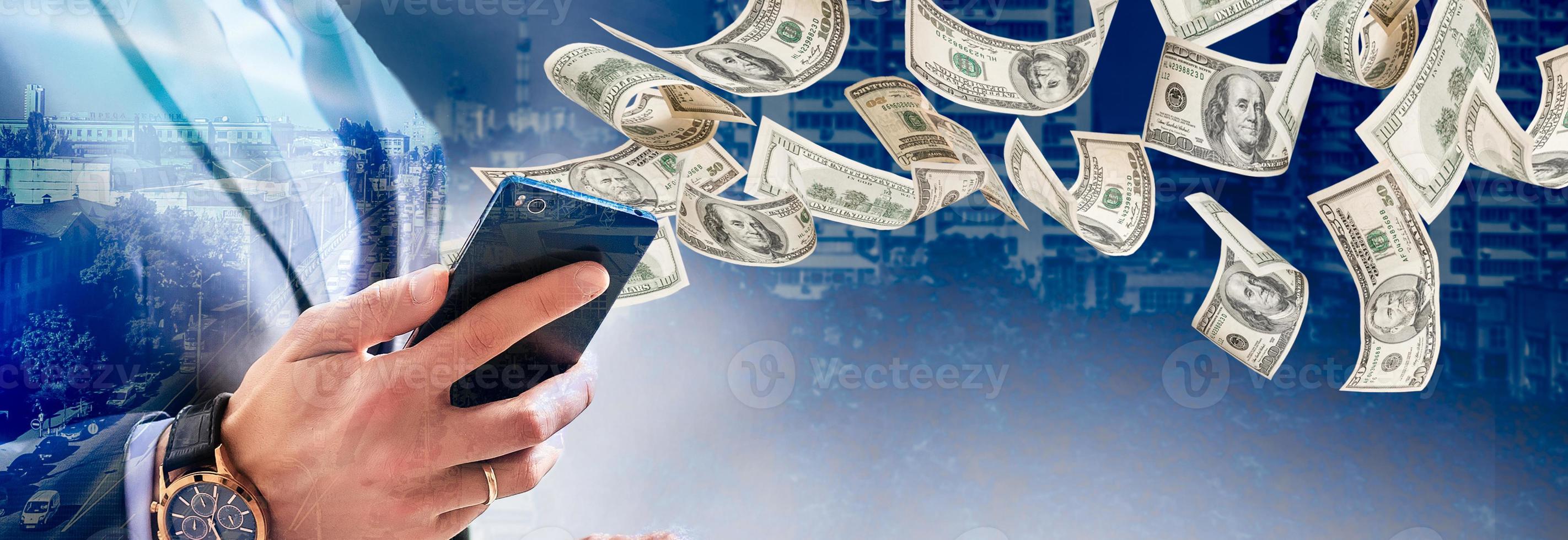 Technology online banking money transfer, e-commerce concept. Happy young man using smartphone with dollar bills flying away from screen isolated office background photo