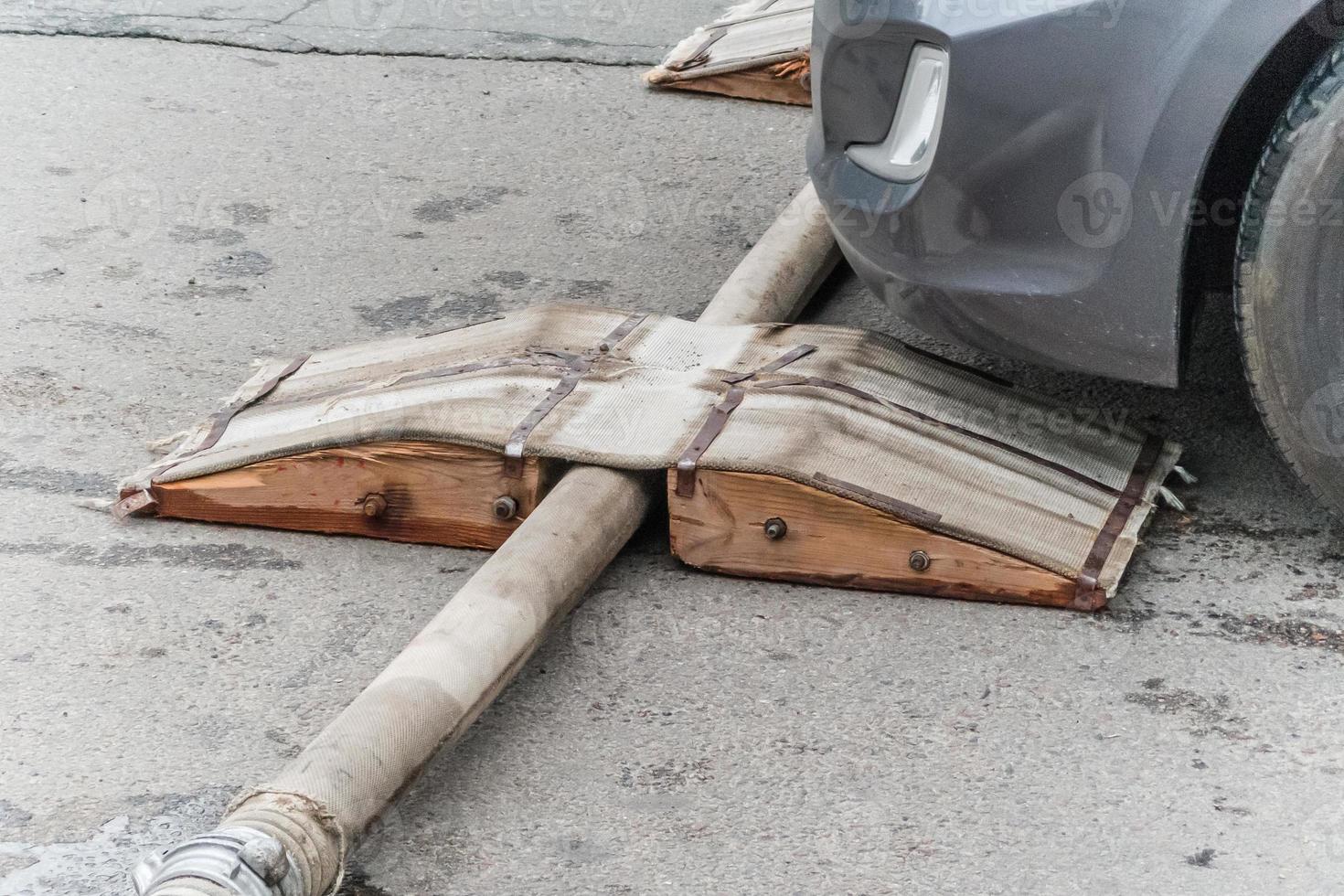 An emergency triangular orange cone denoting danger and a fire hose lie on the stone floor, the road photo