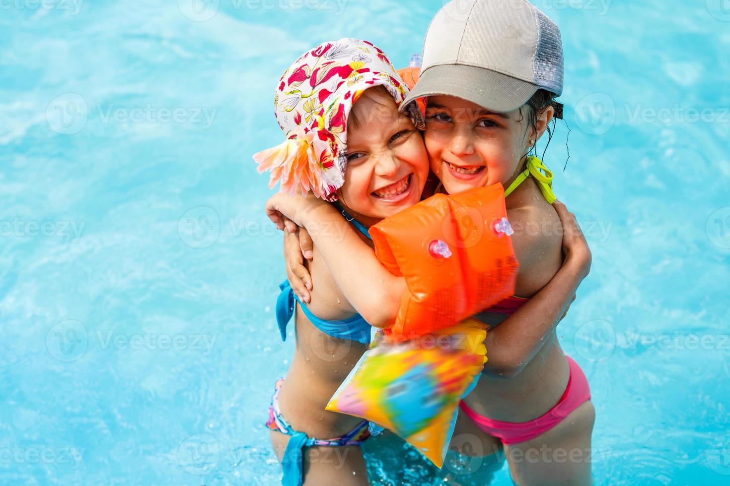 Children playing in pool. Two little girls having fun in the pool. Summer holidays and vacation concept photo