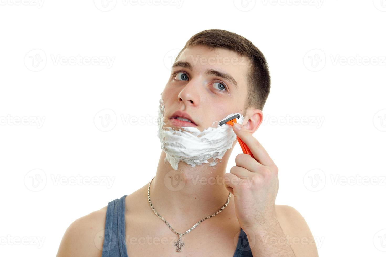 Portrait of guy with foam on his face who shaves his beard close-up photo