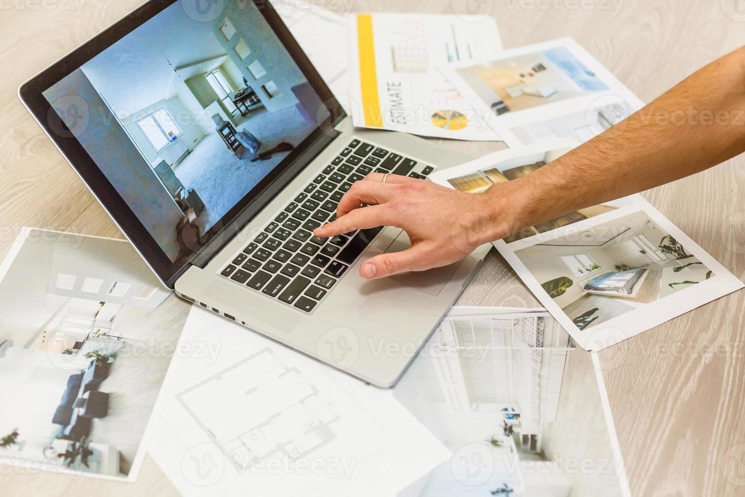 Decorator's hands with ruler on project drawings. Laptop, color swatches and tools on work table photo