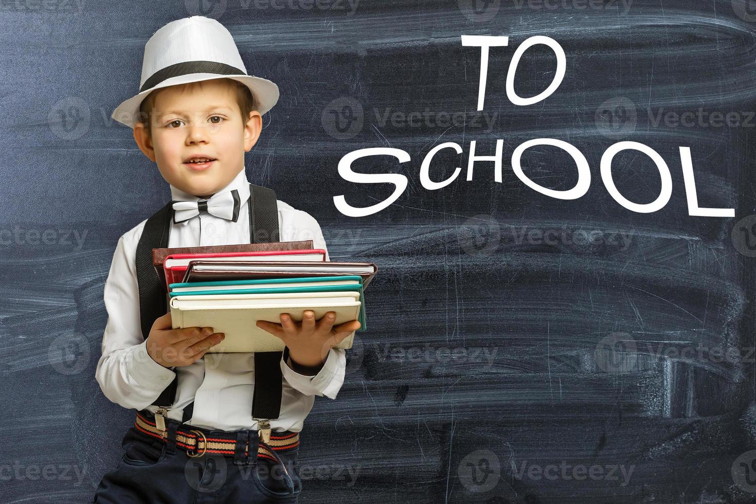 Back to school. Funny little boy in glasses pointing up on black photo