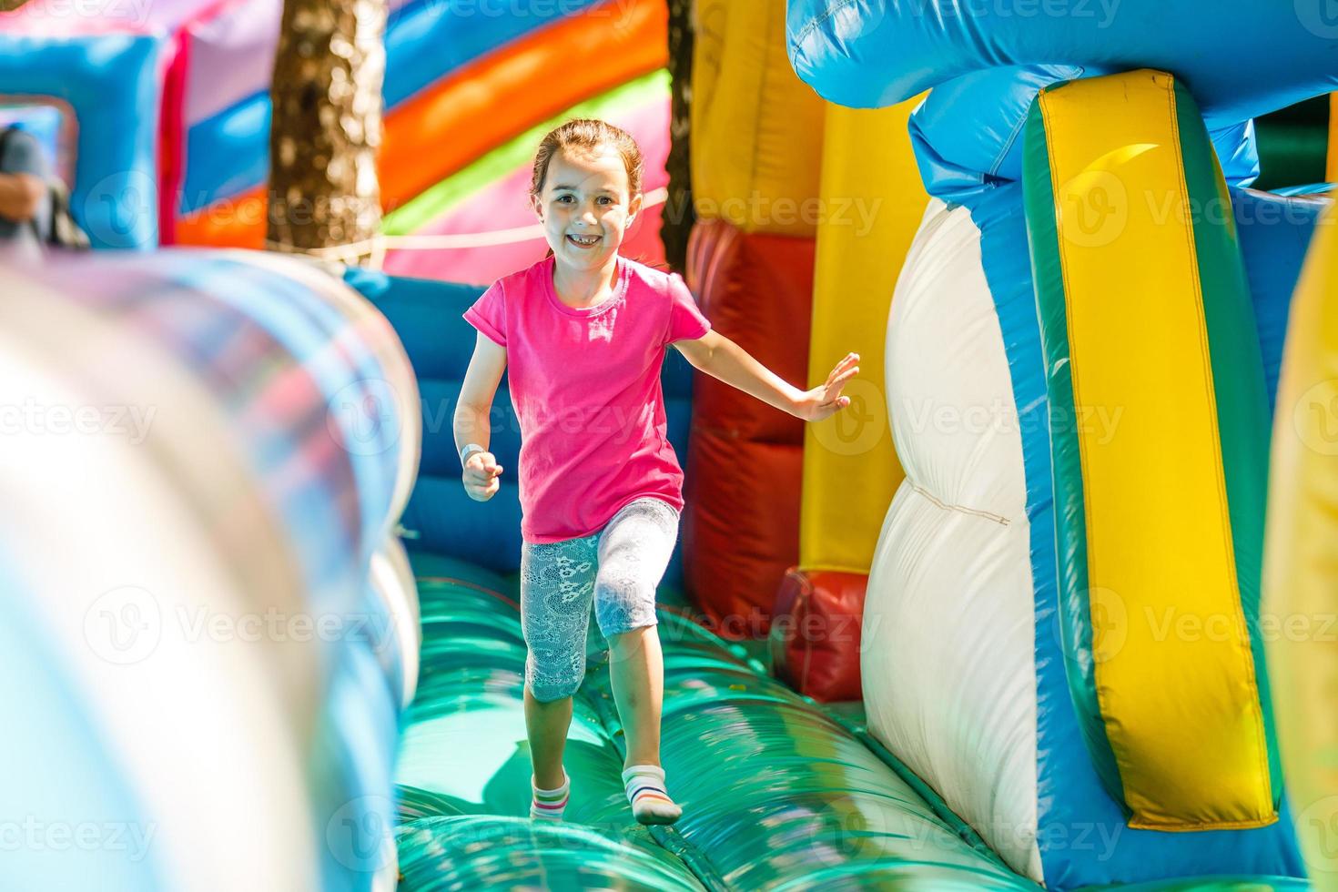 Happy little girl having lots of fun on a jumping castle during sliding. photo