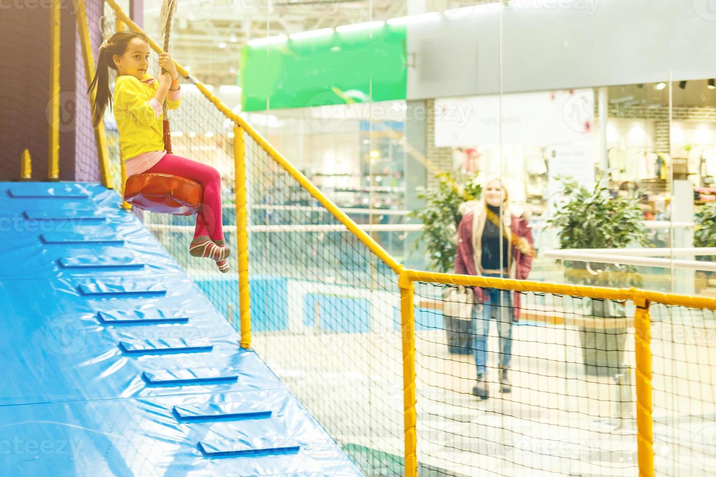 Adorable Little girl laughing happily, riding upside down on a bungee swing on the playground in yellow. Happiness, freedom, enjoyment, health. photo