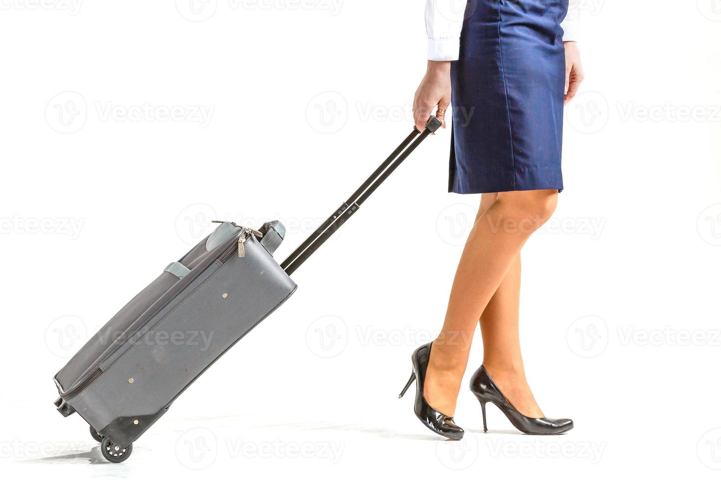 The stewardess goes and rolls her suitcase. White background photo