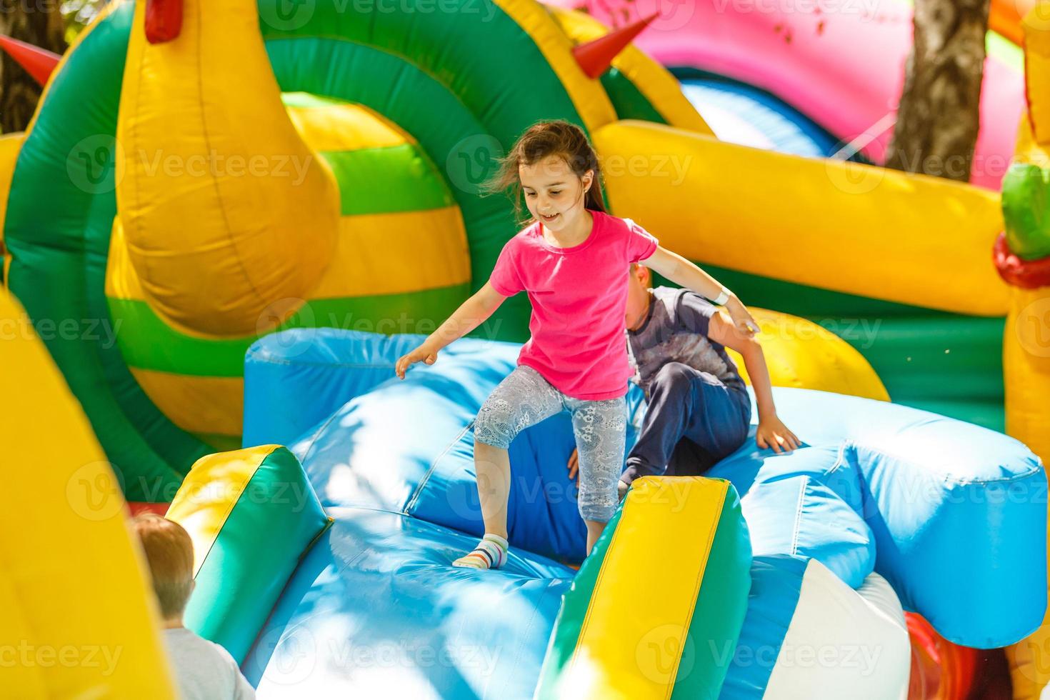 niña feliz divirtiéndose mucho en un castillo de salto durante el deslizamiento. foto