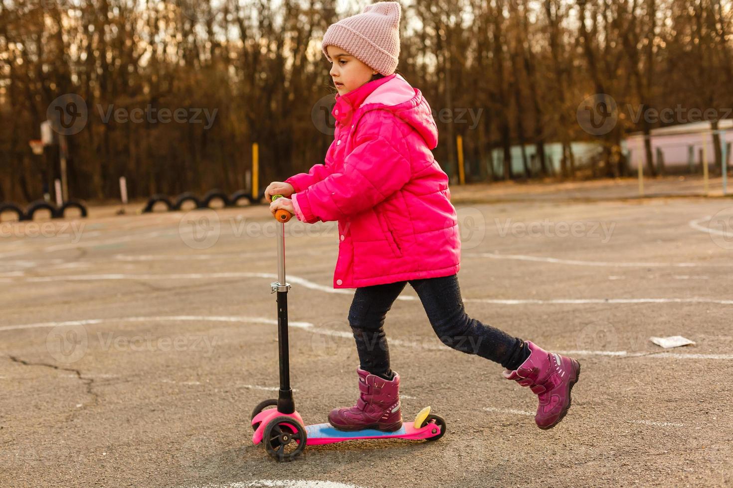 little beautiful girl riding scooter at stadium photo