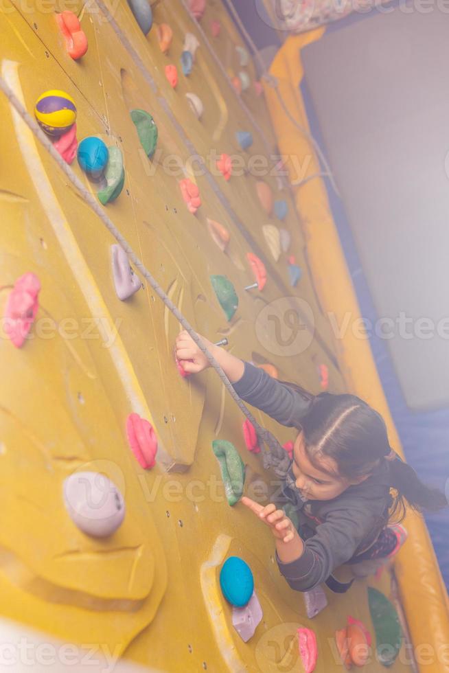 Little girl ascending in outdoor rock climbing gym photo