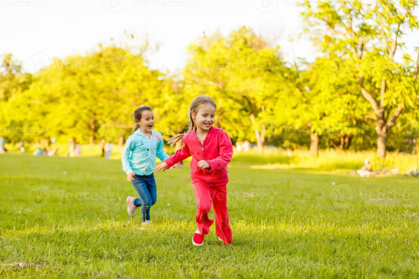 Children run on the green grass holding hands. Girls running around the lawn with grass playing with splashes of water to water plants. photo