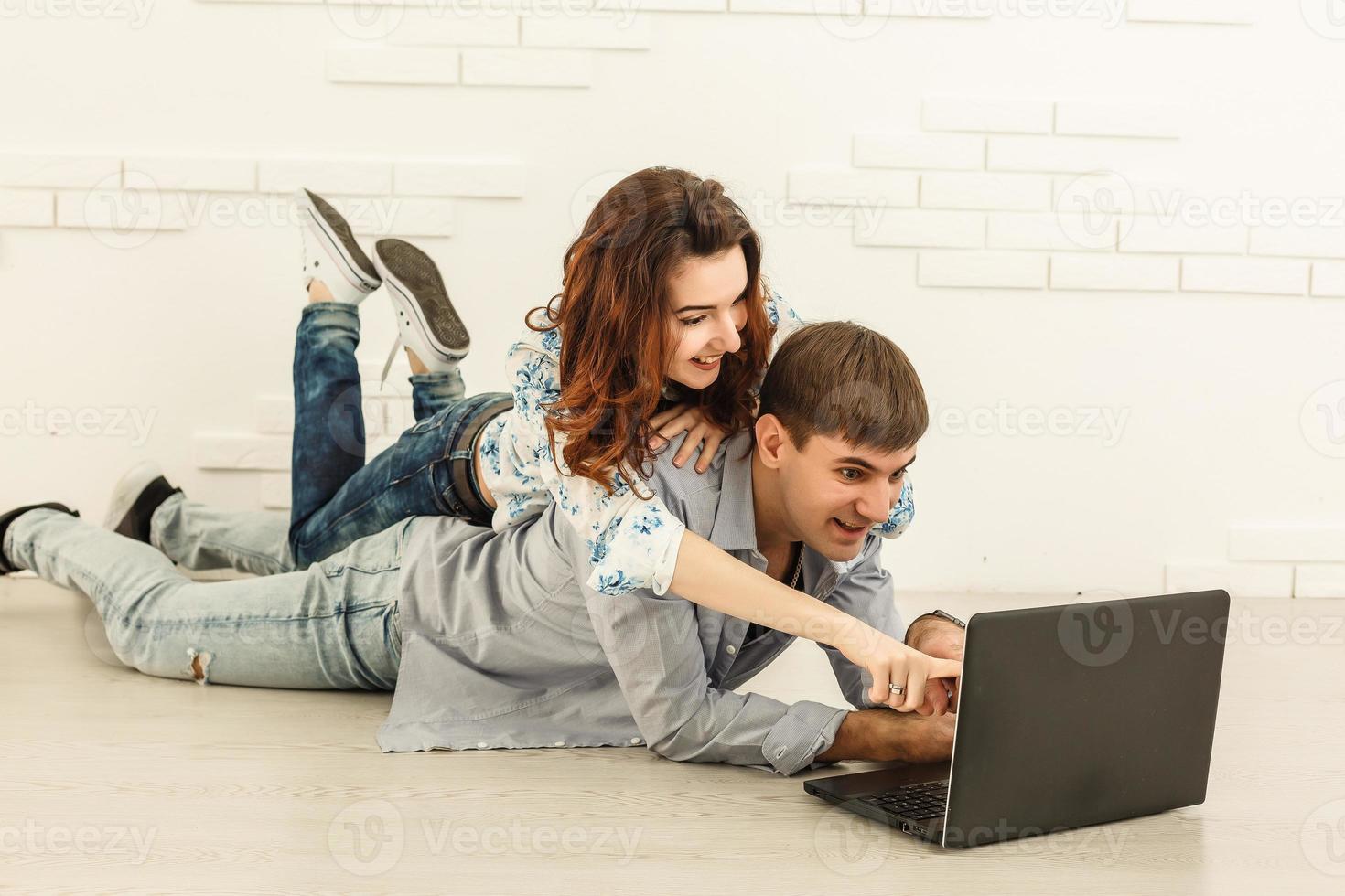 Couple shopping online at laptop computer - Two young friends watching a video on a notebook in the living room photo