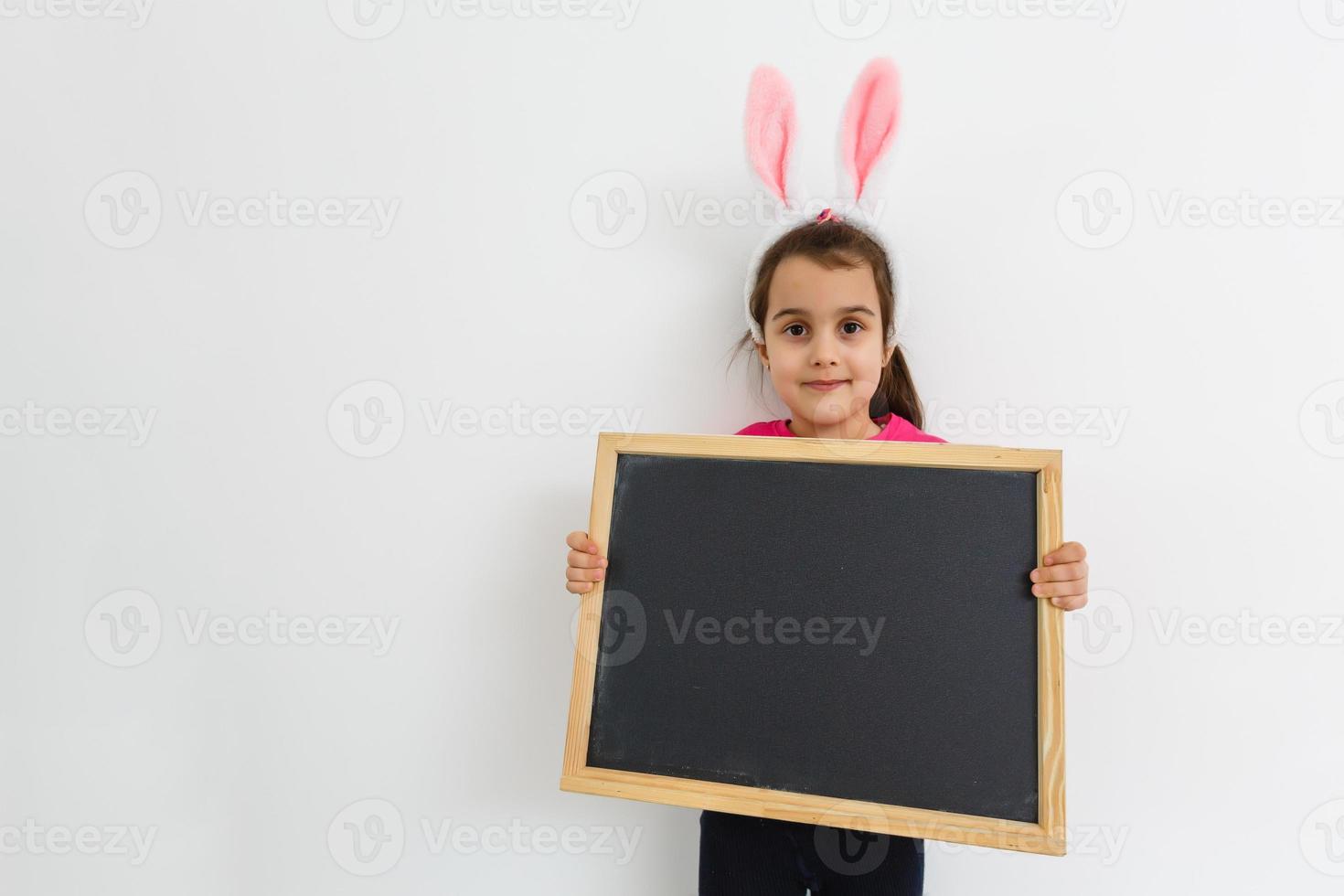 Little girl playing Baby on Easter egg hunt Kids play . Heart form blank chalk board for your text photo