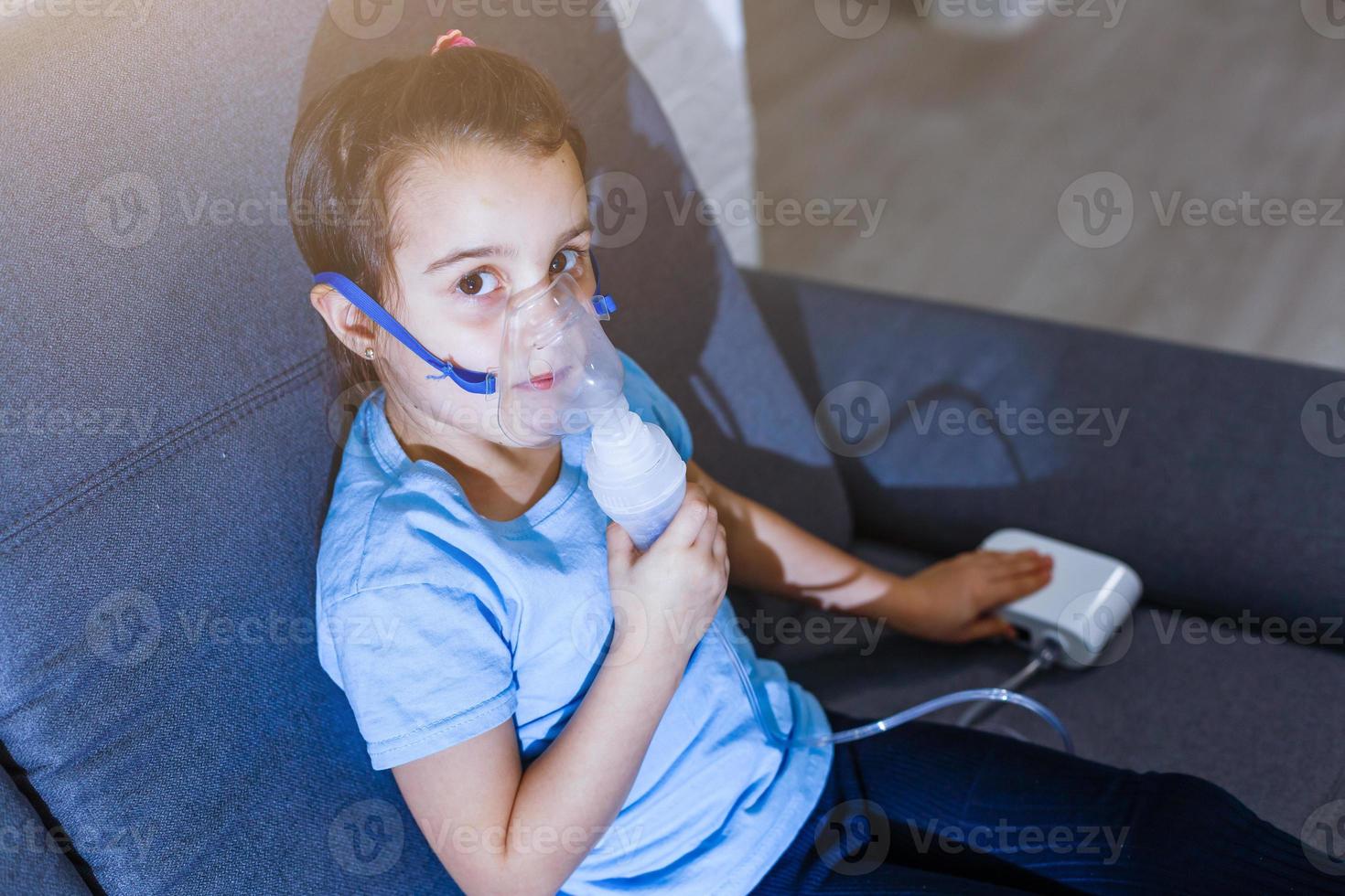la niña caucásica respira con una máscara especial, que ayuda a detener el ataque de asma o aliviar los síntomas de la enfermedad respiratoria. foto