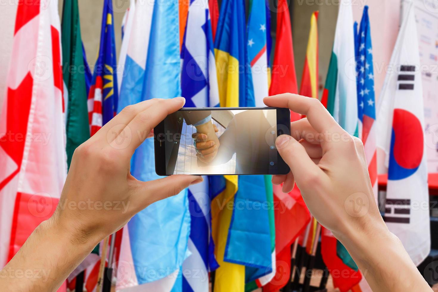 las manos de los hombres hacen una fotografía telefónica de la bandera foto