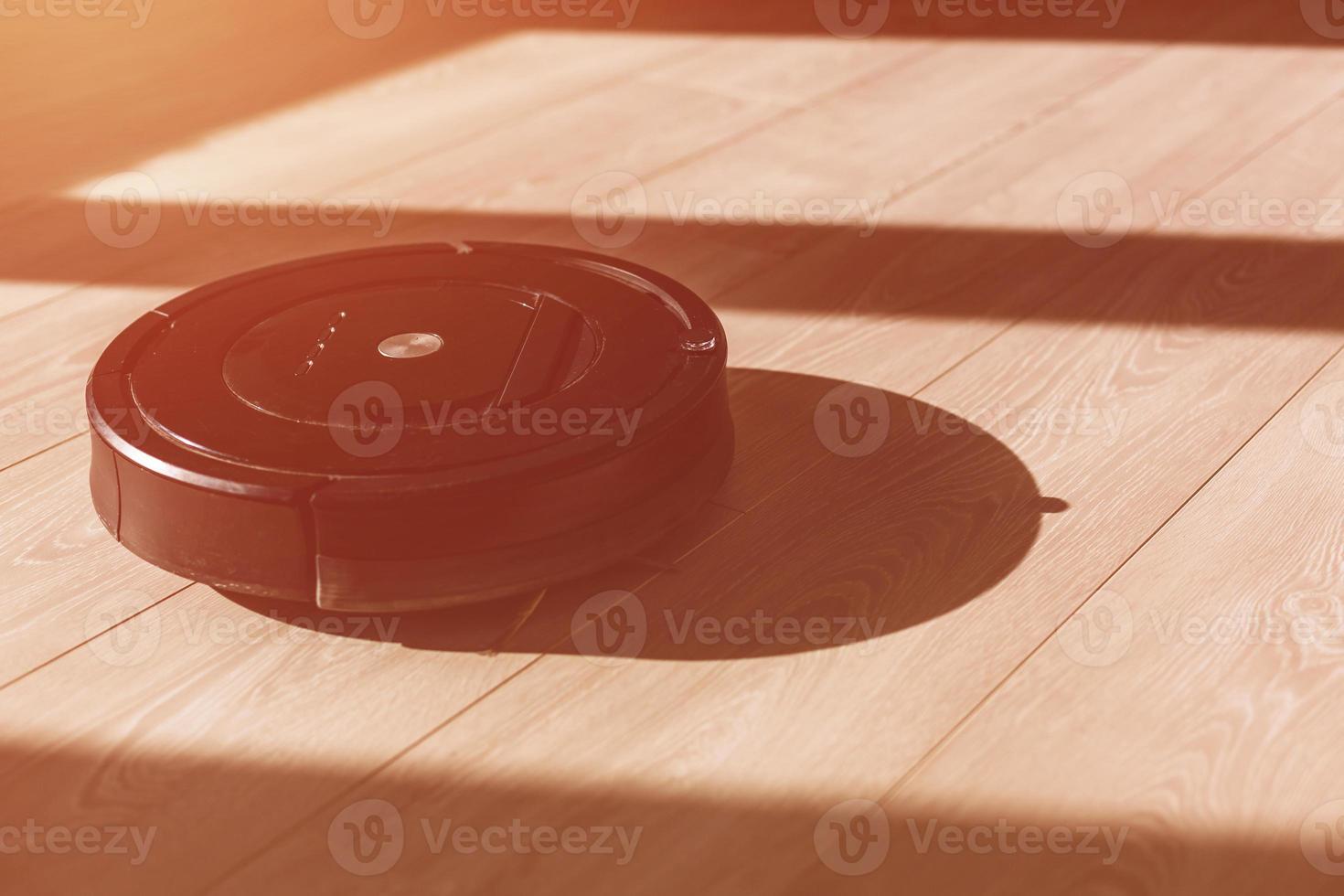 New Clean Robot vacuum cleaner on laminate wood floor, Smart robotic automate wireless cleaning technology machine in living room. photo