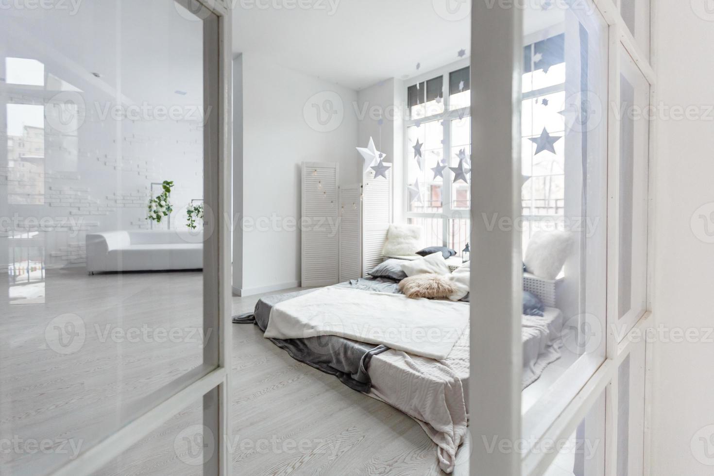 Sunny morning in a natural style bedroom interior with a bed, bunch of wild flowers. Big bright window in the background. Real photo. photo