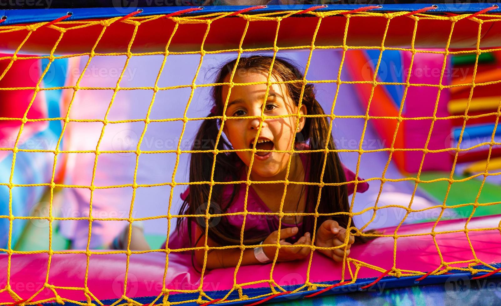 Happy little girl having lots of fun on a jumping castle during sliding photo