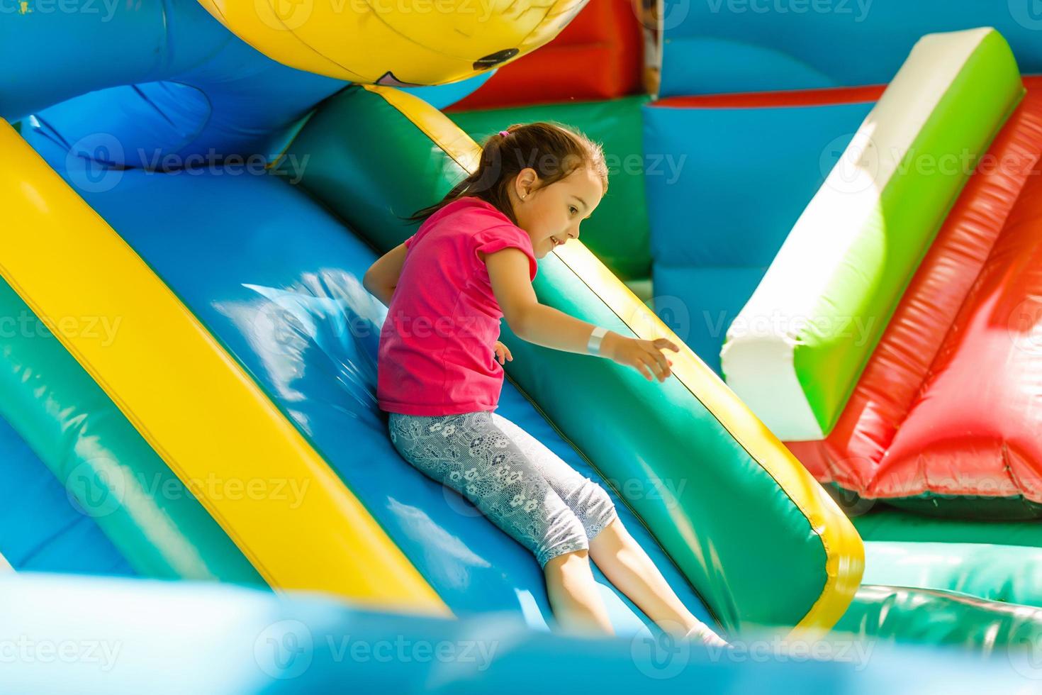 Little Girl sliding down an inflatable Slide photo