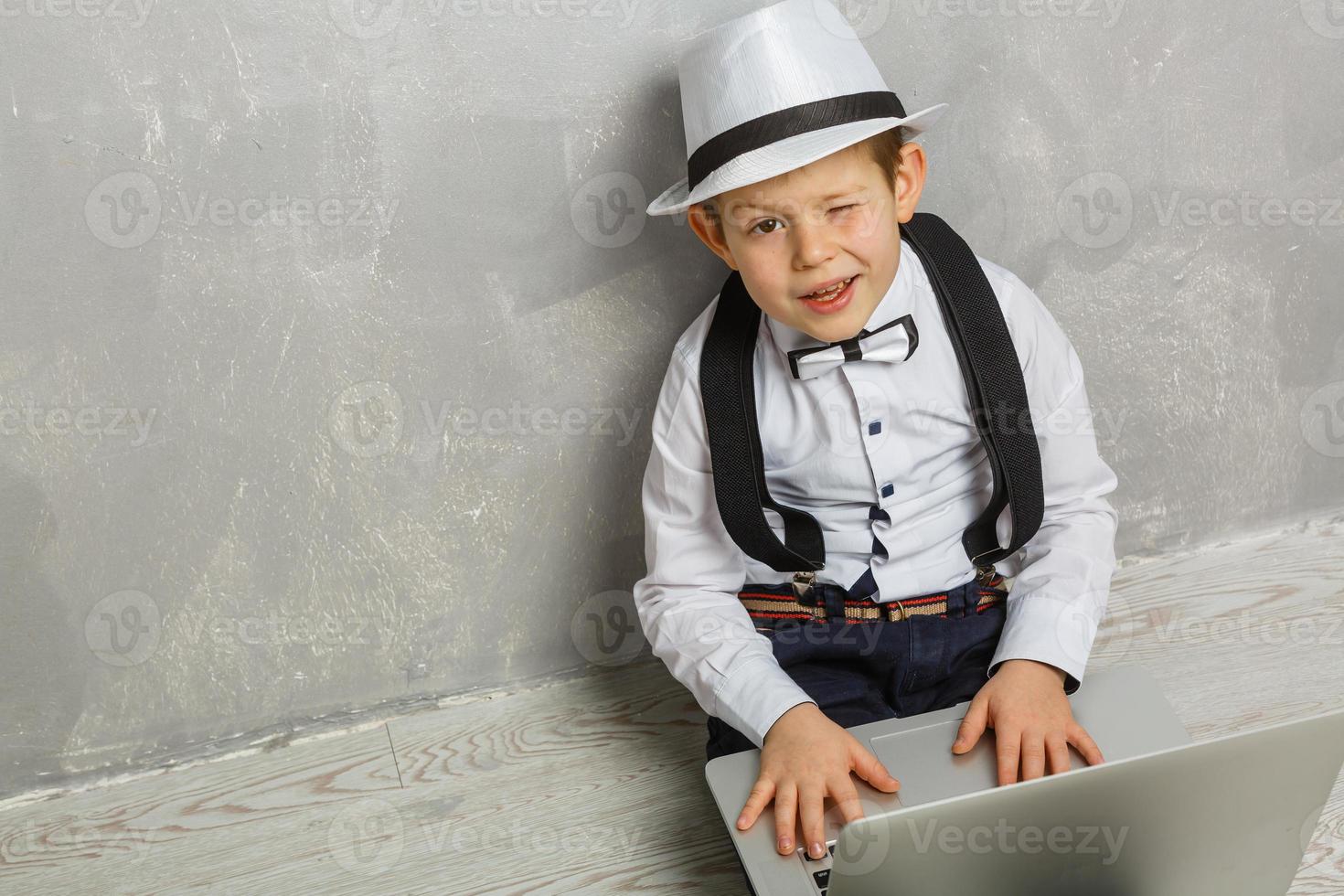 Young man sits on the laminate floor with black laptop. Top view photo