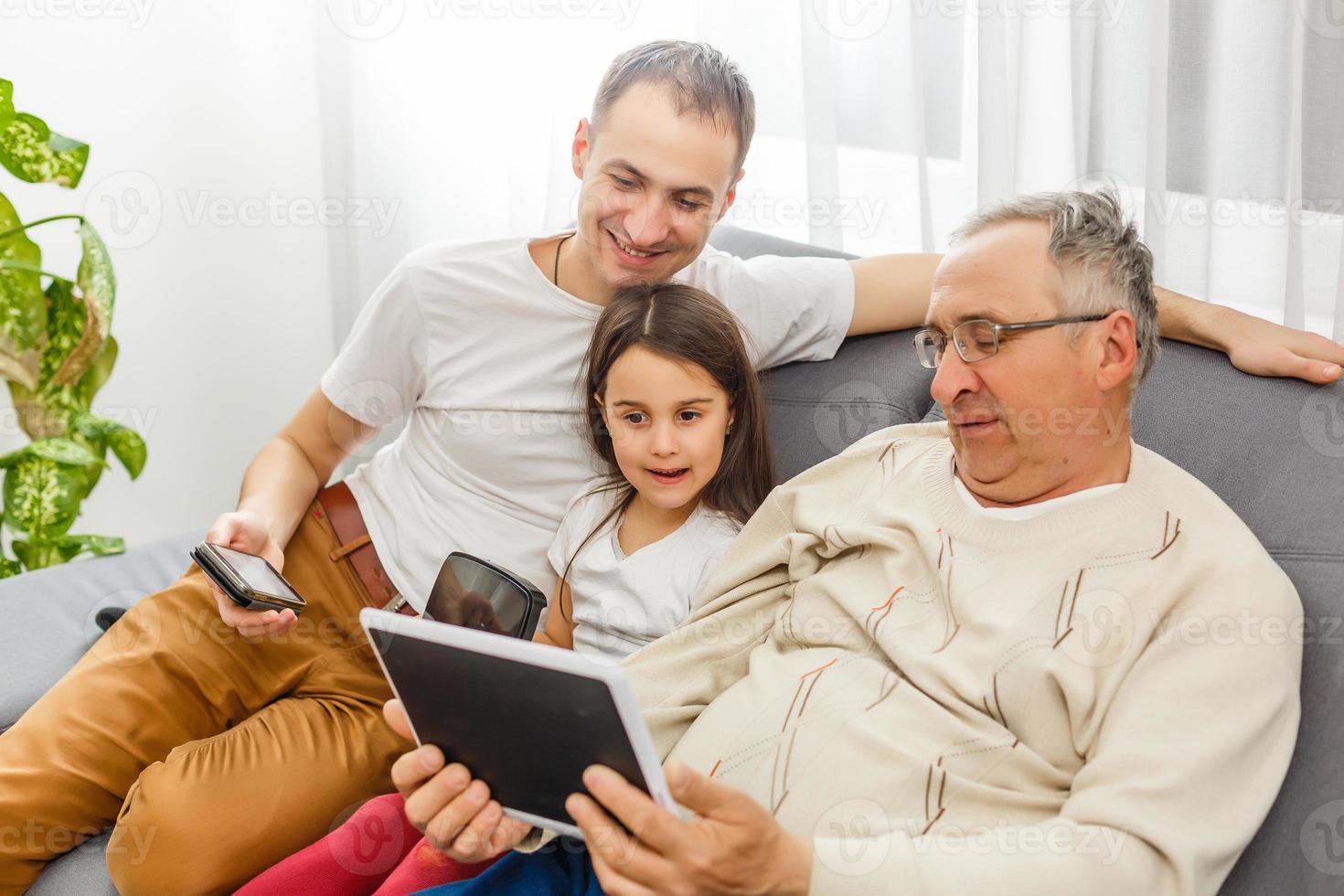 Happy family using a tablet computer in a living room photo