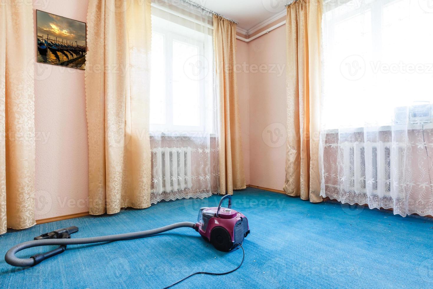 vacuum cleaner standing on parquet floor in front of sofa in living room photo