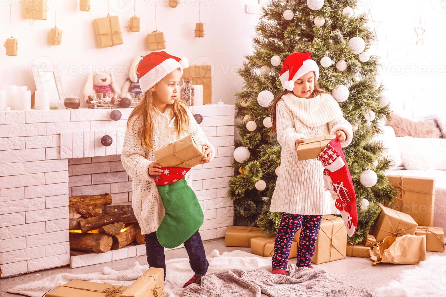 las hermanas pequeñas de los niños sostienen el fondo interior de las cajas de regalos. que gran sorpresa pequeñas niñas lindas recibieron regalos navideños. mejores juguetes y regalos de navidad. niños amigos emocionados desempacando sus regalos. foto