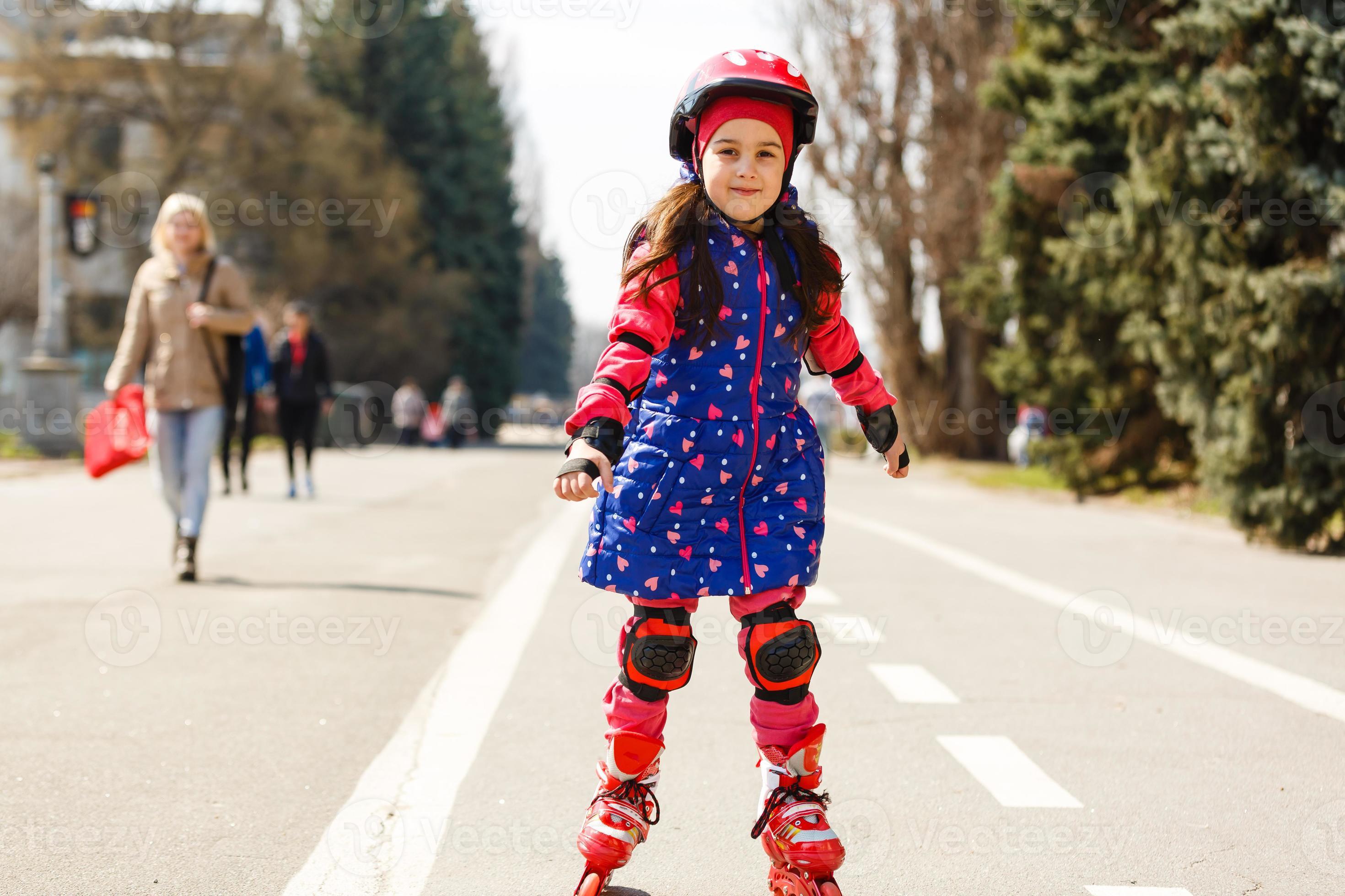 niña bonita y graciosa en patines con casco montando en un parque, casco  patines niña