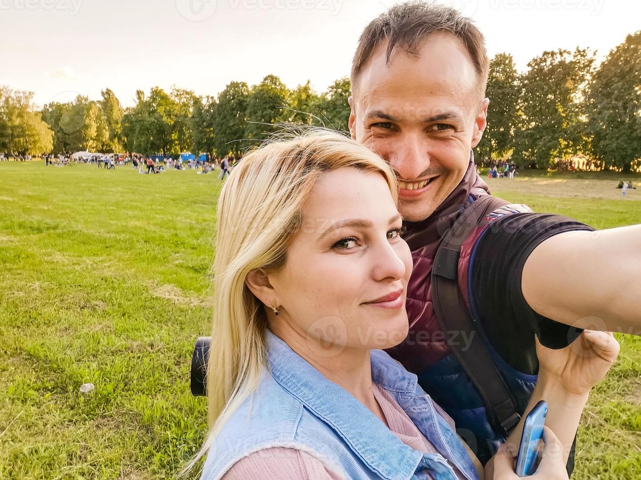 Happy young couple hugging. Man and woman making selfies isolated on green background photo