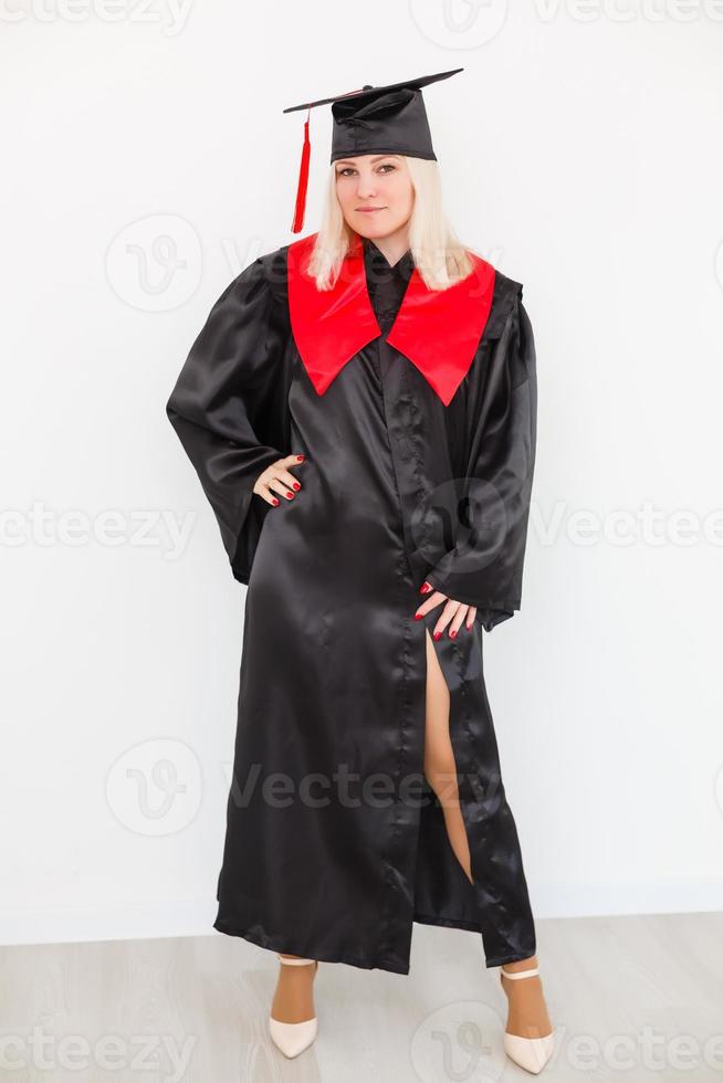 emocionada feliz estudiante graduada está de pie en el manto, sonriendo y mirando a la cámara foto