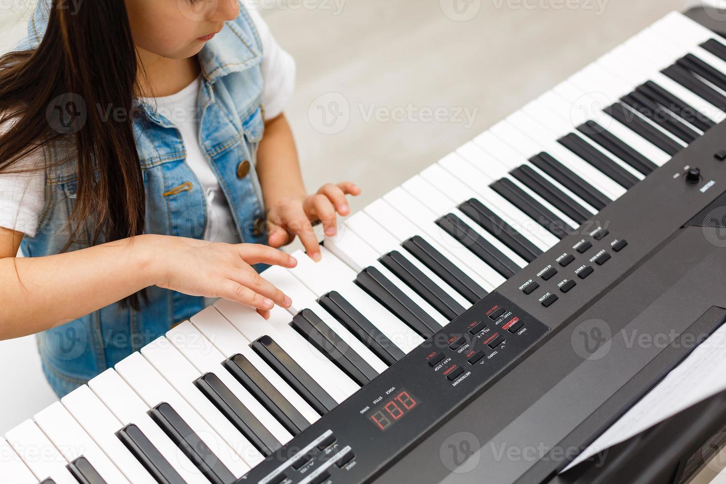 linda niña toca el piano, sintetizador. capacitación. educación. escuela. formación estética. aula de primaria. foto