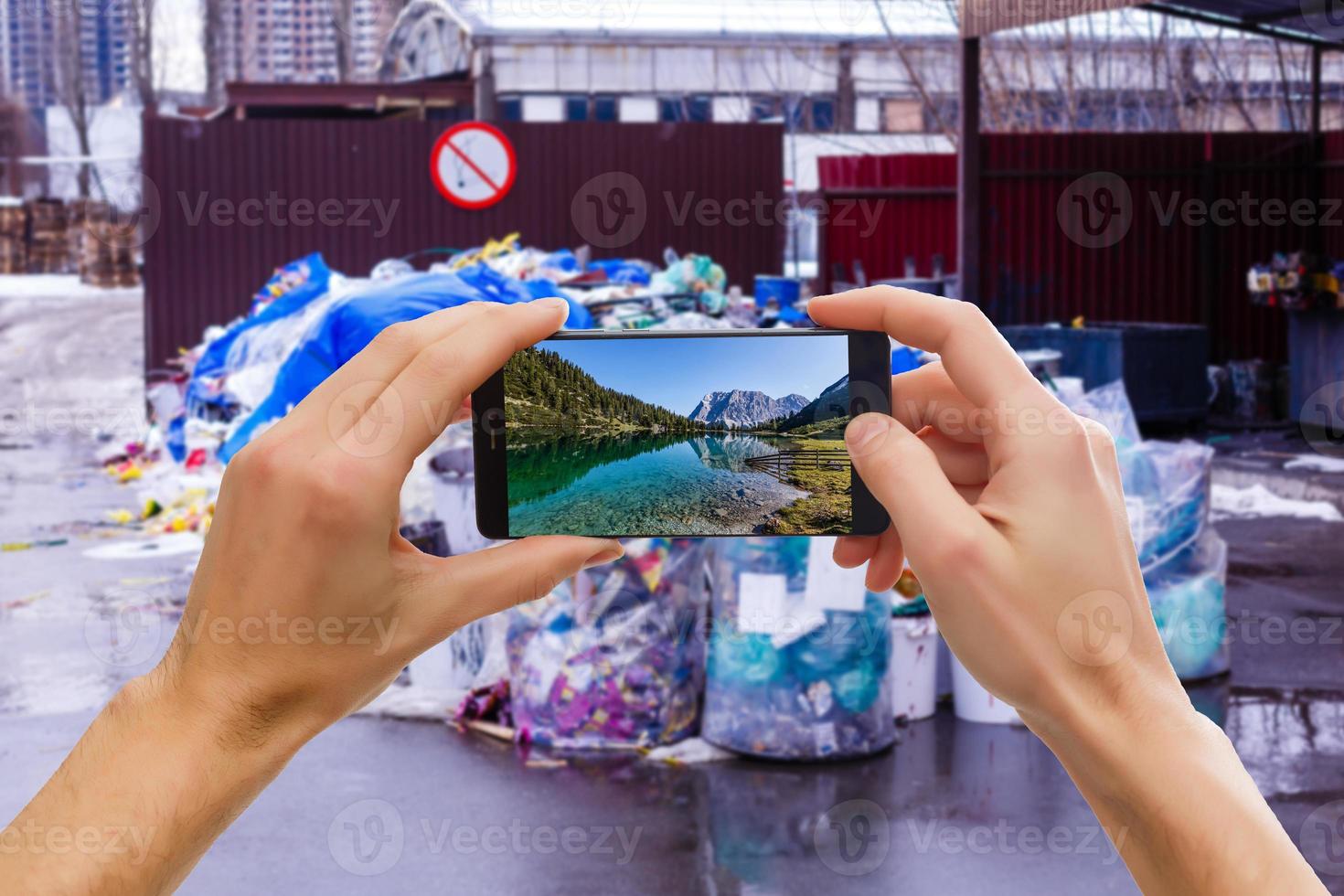 mano con smartphnoe tome una foto para topadora en el vertedero de basura.